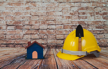 Yellow construction helmet on wood and old brick wall