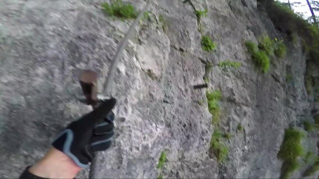 POV - a man climbs up a cliff in a forest and rearranges the carabiners