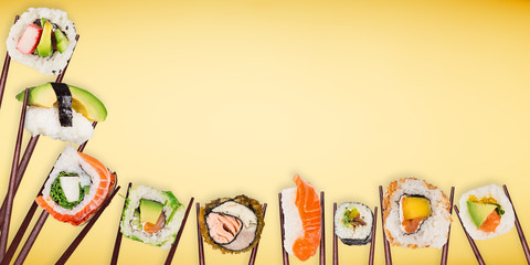 Traditional japanese sushi pieces placed between chopsticks on pastel color background.