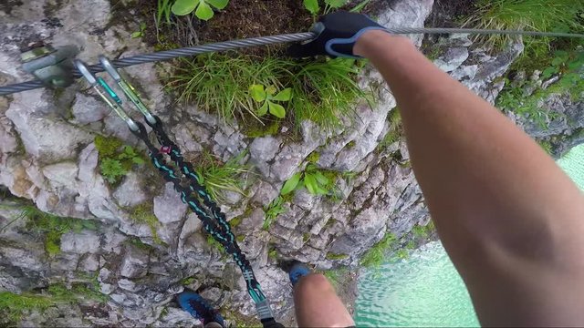 POV - a man climbs alongside a cliff above a river