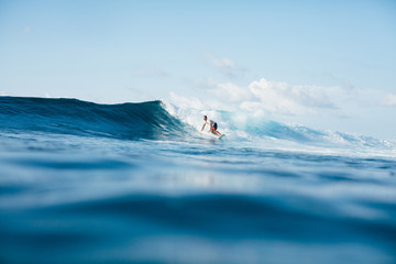 handsome athletic man surfing on blue wave - obrazy, fototapety, plakaty
