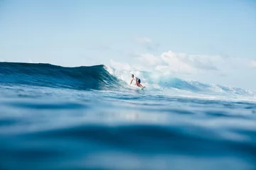 Fototapeten handsome athletic man surfing on blue wave © LIGHTFIELD STUDIOS