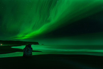 The Northern Light at the Vik Cliffs Iceland. Landscape of Vik beach, with green bands of Aurora Borealis. Night Seascape a paradise for travel and vacations.