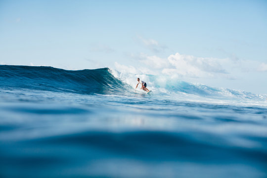 handsome athletic man surfing on blue wave