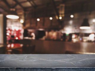 Empty black marble stone table top and blurred bokeh cafe and coffee shop interior background with...