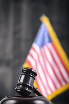 Judge Gavel and United States of America flag on a black wooden background.