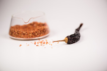 Coarsely ground chilli peppers in glass bowl isolated on white background.