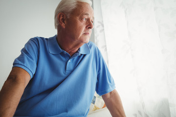 Thoughtful senior man sitting on his bed