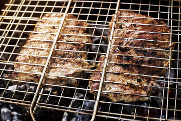 Two beef steaks on the grid are prepared on the grill outdoor - a family barbecue. Summer fresh aromatic dishes