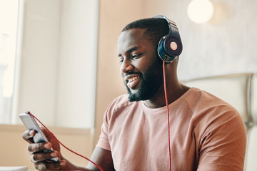 Portret of afro american man wearing headphones and holding a phone. © Мария Кокулина