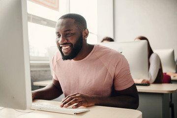 Afro amaican man usig laptop in office and smile.Have sucess.