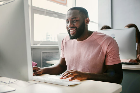 Happy Man Sitting At Computer In Office.