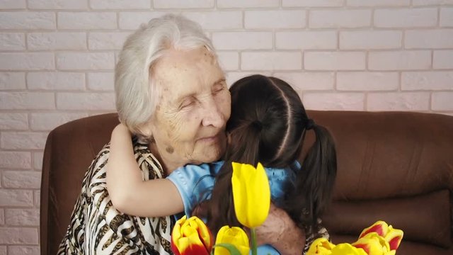 Child with a grandmother. Granddaughter gives flowers to grandmothers.