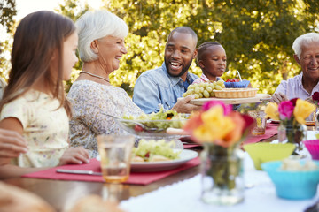 Family and friends talking over lunch at a table in garden