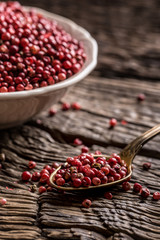 Red peppercorn in bowl and spoon on oak table