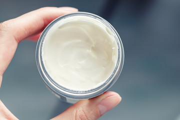 Women's hand holding a jar of cream