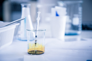 Syringe in the beaker with yellow chemical liquid