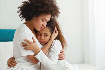 Mother comforting her daughter, sitting in the bedroom, hugging  - Powered by Adobe