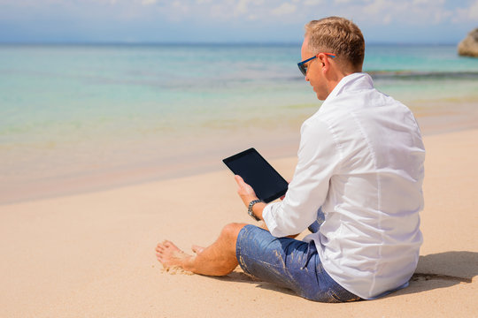 Businessman with tablet on the beach