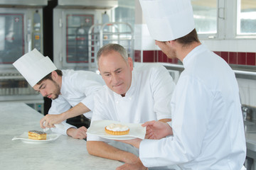 chef assessping pudding made by trainee chef