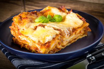 Piece of tasty hot lasagna with red wine.