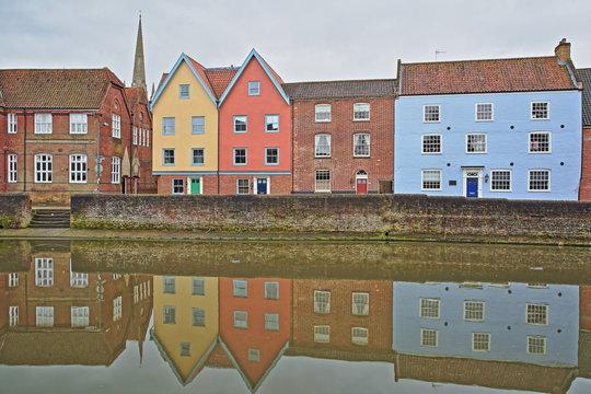 The riverside (river Wensum) in Norwich (Norfolk, UK) with reflections of colorful houses and the tower and spire of the Cathedral in the background