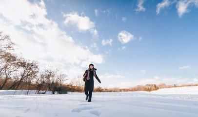 Obraz premium Young pretty girl tourist with backpack goes through the snowy forest, the concept of a healthy lifestyle and outdoor activities in winter walks.