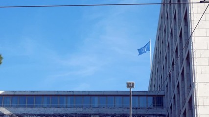 tracking shot on the facade, with the flag of the Fao waving in the blue sky