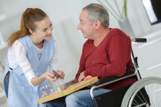 photo of happy elderly man with disability and helpful nurse