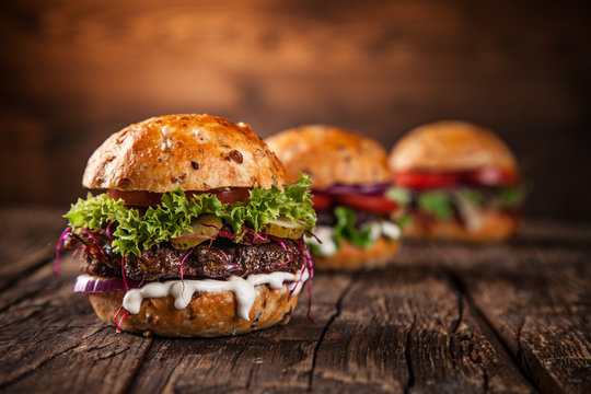 Tasty burgers on wooden table.