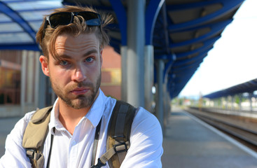 Young man standing on platform at train station