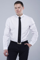 Young handsome man in a shirt with a tie on a light gray background