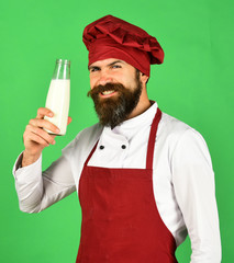 Man with beard holds glass bottle on green background.