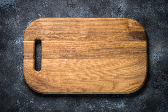 Wooden cutting board on black stone table top view.