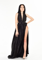 Fototapeta premium Lady, sexy girl in dress. Attractive girl wears expensive fashionable evening dress with erotic slit. Fashion dress concept. Woman in elegant black long evening dress with decollete, white background.