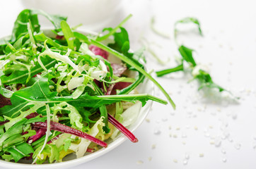 Salad from fresh herbs, arugula, lettuce, salt and sesame in white bowl. Vegetarian, dietary dish