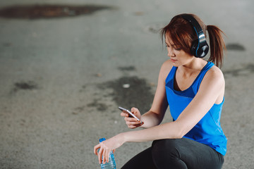 Young woman resting and drinking water after jogging