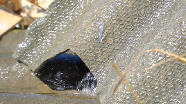 Drops of water flowing down the gutter. Slow motion