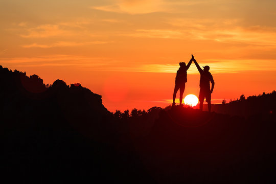 Teamwork couple celebrating in inspiring mountains sunset