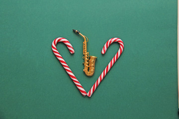New Year's card - golden saxophone and candy cane. Green background