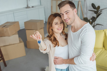 Happy Young Couple Smiling At Camera While Holding Key From New Apartment Happy Young Couple Smiling At Camera While Holding Key From New Apartment