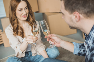 happy young couple clinking glasses of champagne while celebrating relocation