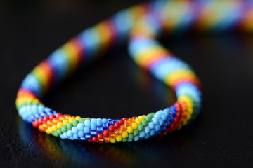 Colorful necklace rainbow colors on a dark background close up