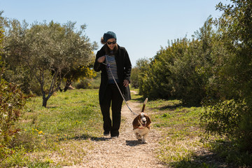 Naklejka na ściany i meble Girl and her basset hound dog walking along the camp in the winter sun