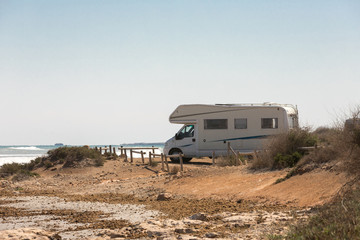 Caravan motorhome parked on the beach in front of the blue sea in a beautiful place of wild nature