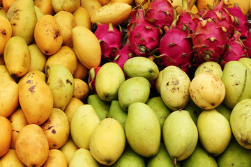 Exotic tropical fruits (mango, dragon fruit) closeup on a market, top view.