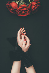 Female hands tied with ribbon and rose flowers isolated on black