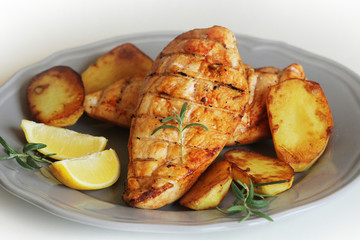 Grilled chicken breast with fried potato and lemon