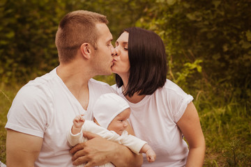 Young parents and a newborn baby together, and nature
