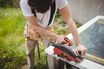 Carpenter cutting wooden frame from circular saw